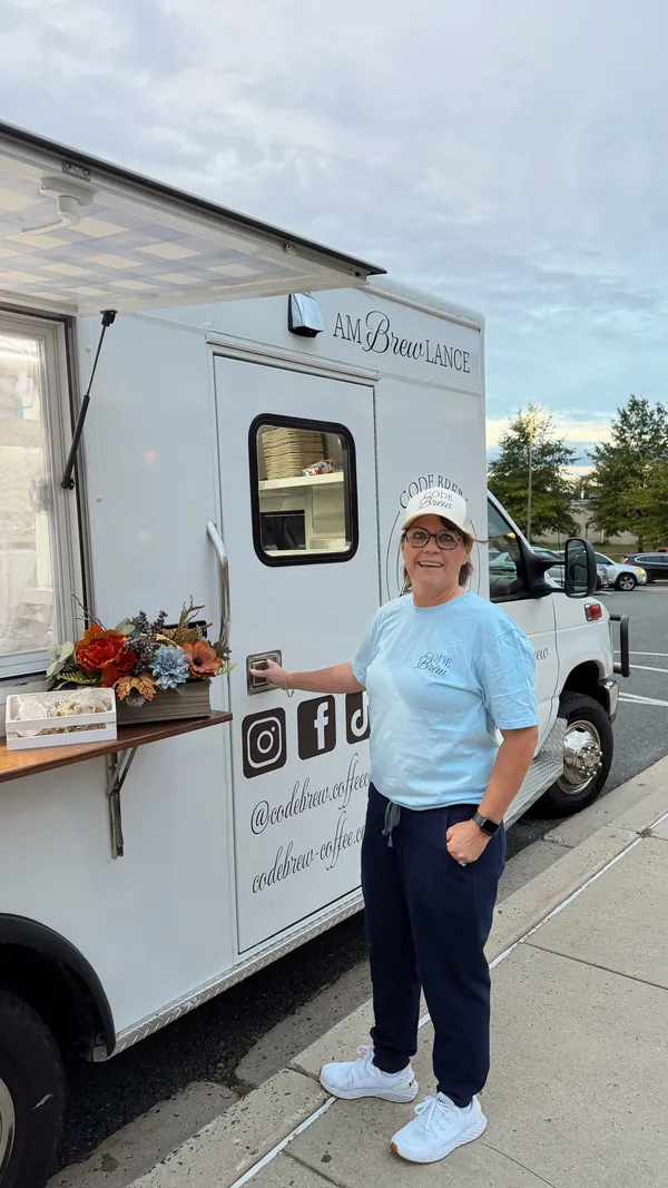 Deb at the side door of the finished amBREWlance, under its awning, next to the Code Brew socials decal