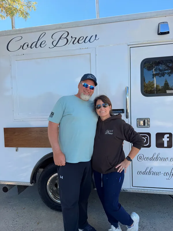 Rick and Deb in Code Brew gear, smiling in front of the finished amBREWlance with Code Brew lettered on its side